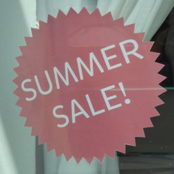 Ein Sticker mit der Aufschrift 'Summer Sale!' an einem Schaufenster.